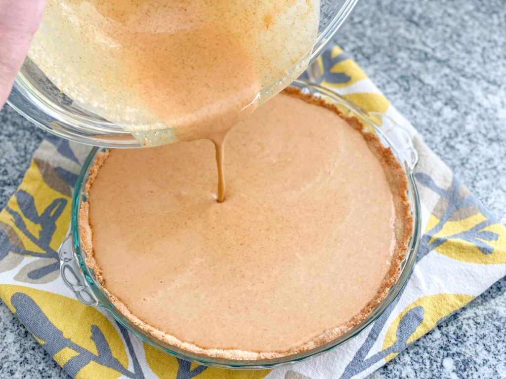 pouring easy keto pumpkin pie filling into pie crust