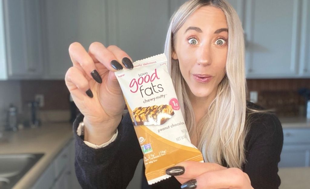 A woman holding a love good fats bar in the wrapper