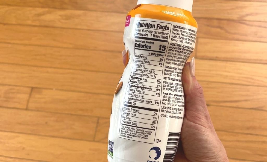 A hand holding a bottle of creamer displaying nutrition information
