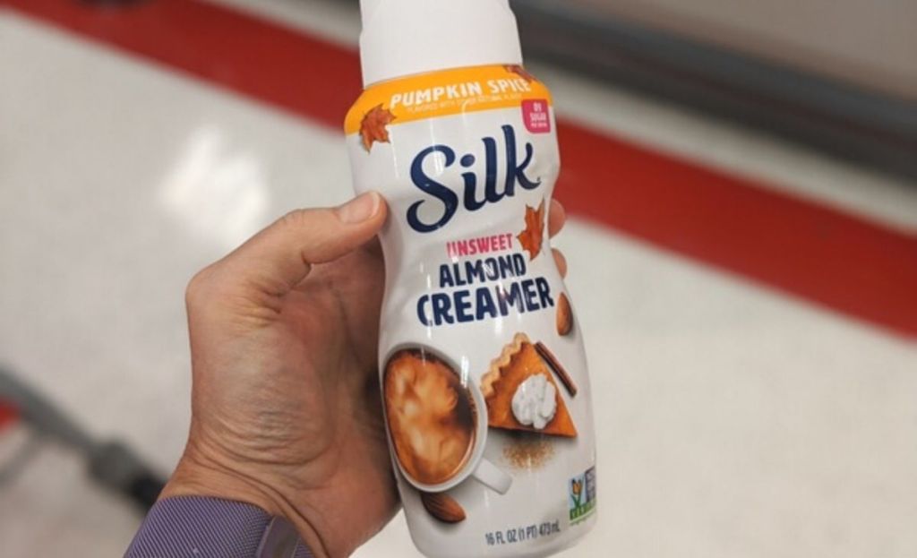 A hand holding a pumpkin spice creamer 