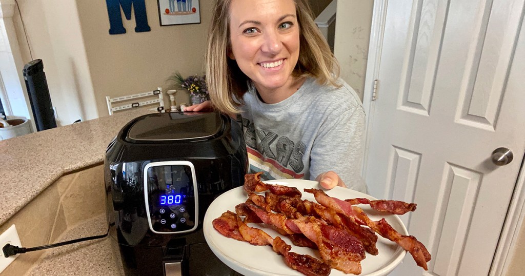 woman holding plate of bacon next to air fryer