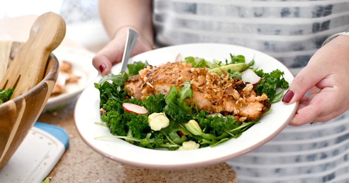 holding a plate of almond crusted salmon salad