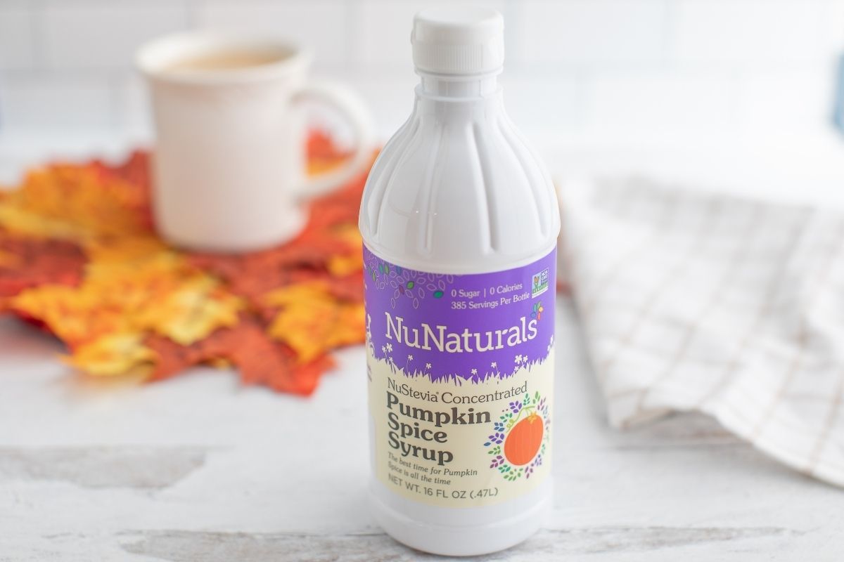 NuNaturals Pumpkin Spice Syrup on table in front of coffee cup and leaves