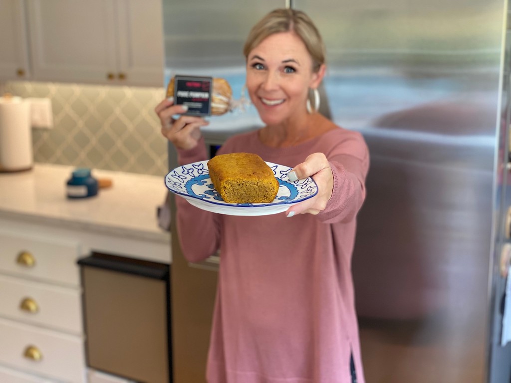 woman smiling while holding loaf of keto pumpkin bread on plate