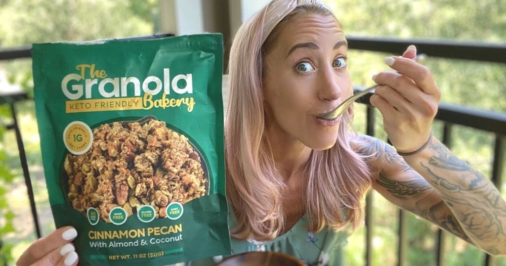 A woman eating a spoonful of granola and holding the bag in the other hand