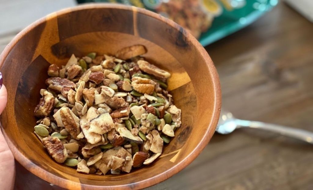 A bowl of granola next to a spoon on a table