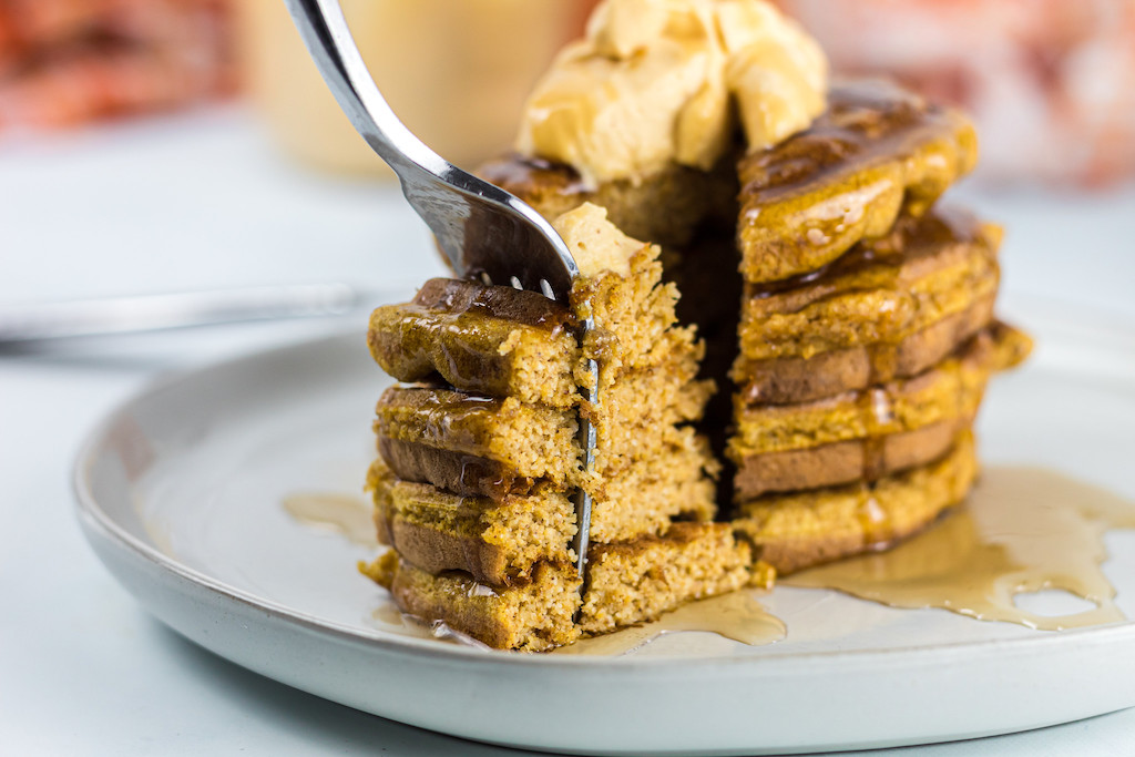 keto pumpkin chaffles stacked with fork taking large bite