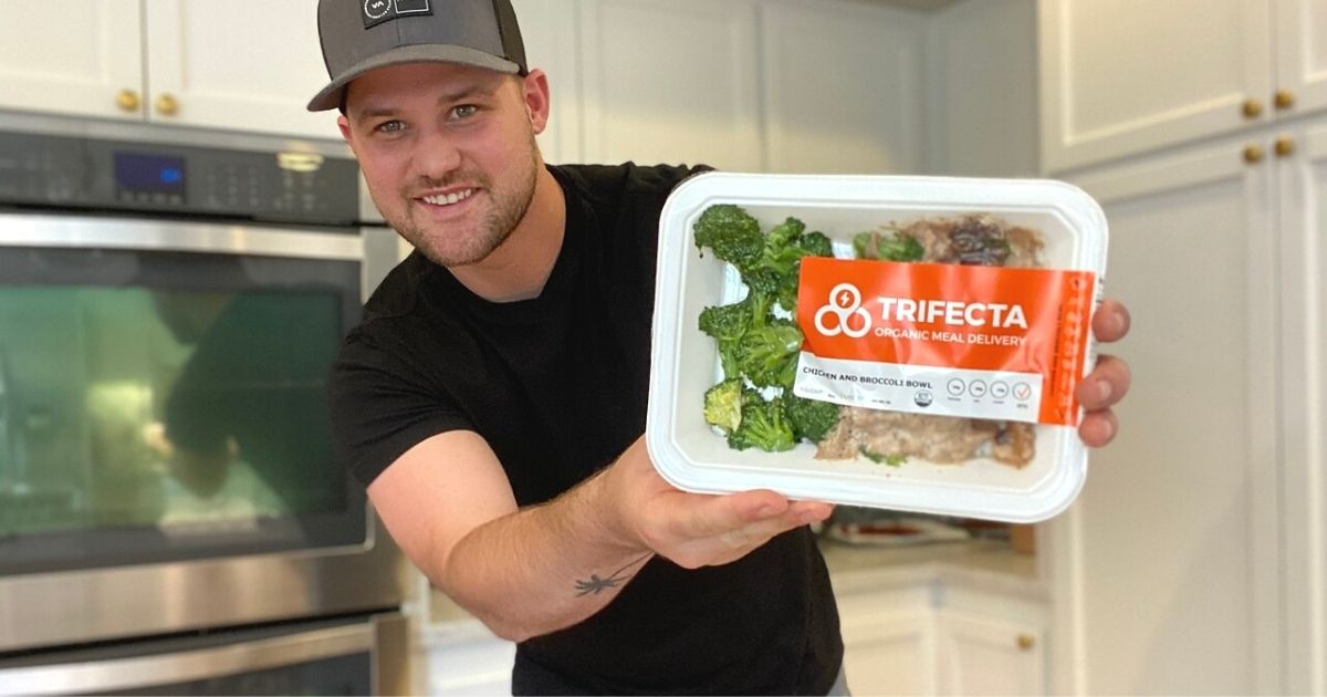 A man holding a pre-made meal in a kitchen