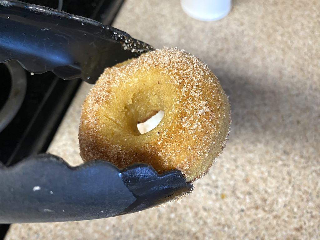 picking up keto pumpkin donut with cinnamon and sugar