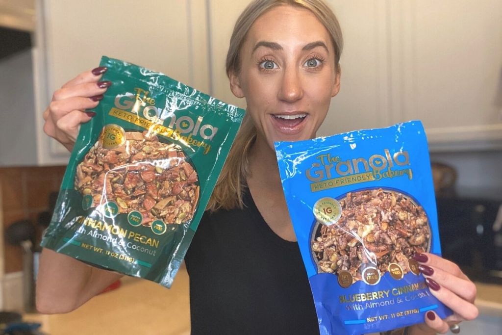A woman holding two bags of granola and smiling