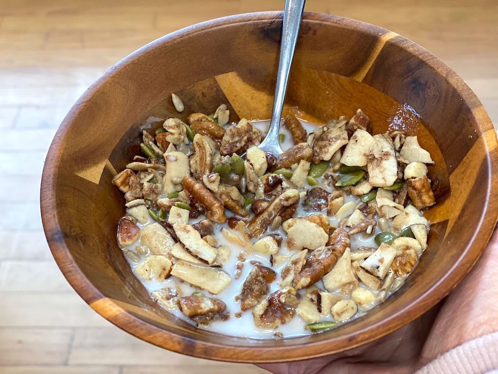 holding bowl of keto granola with almond milk