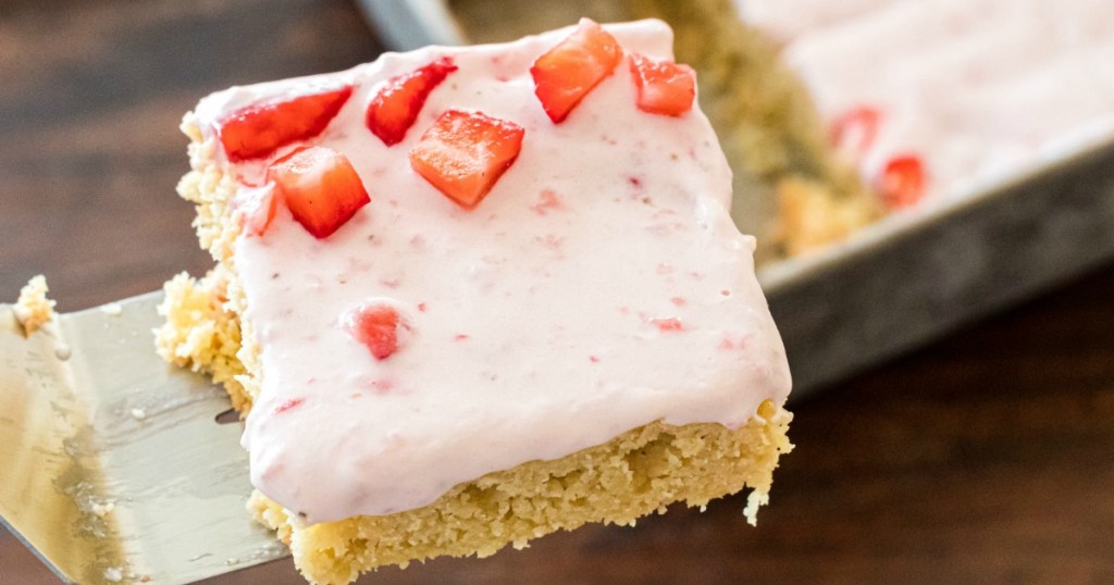 using spatula to pick up keto almond cake with strawberry frosting