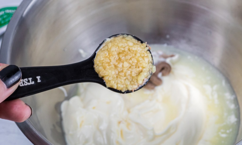 adding minced garlic tablespoon to a mixing bowl