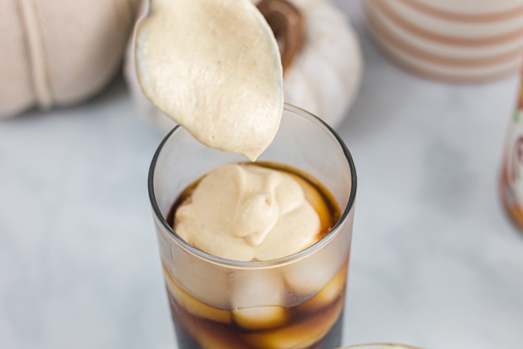 spooning cold foam on top of cold brew