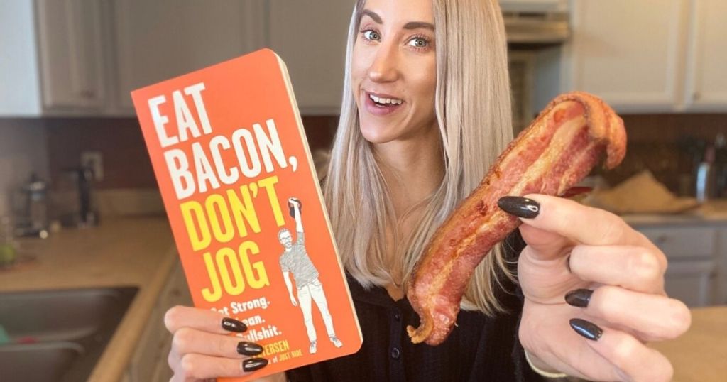 A woman holding a book and a piece of bacon