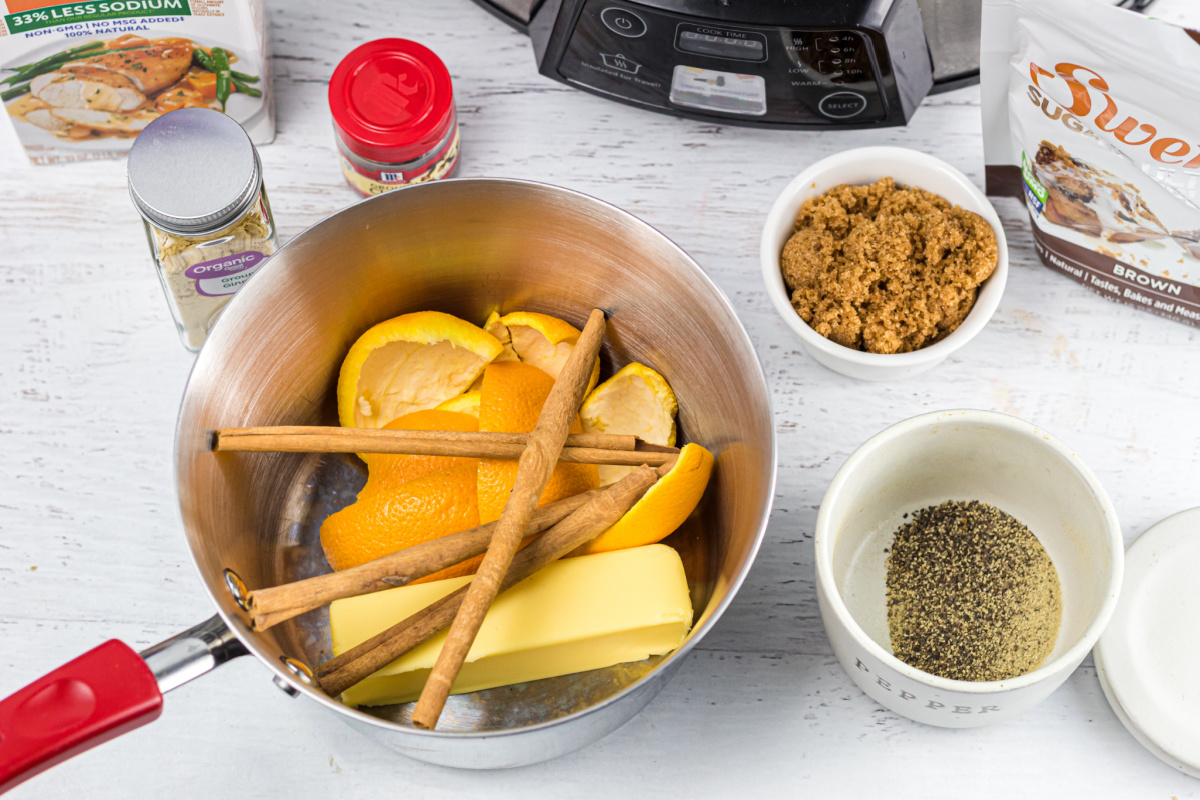 saucepan with ingredients cinnamon, orange peels, and butter for keto ham glaze