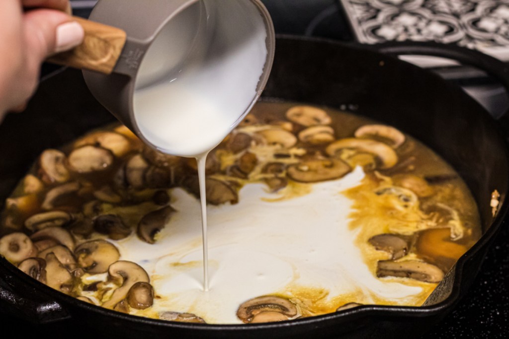 heavy cream being poured into skillet