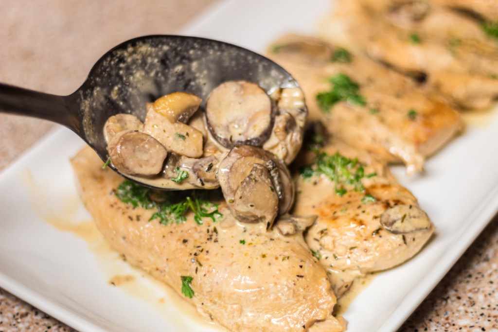 pouring cream sauce on chicken