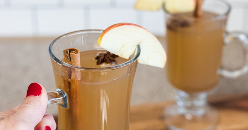 holding glass of keto apple cider