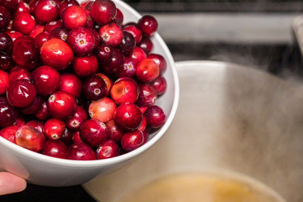 pouring cranberries into saucepan