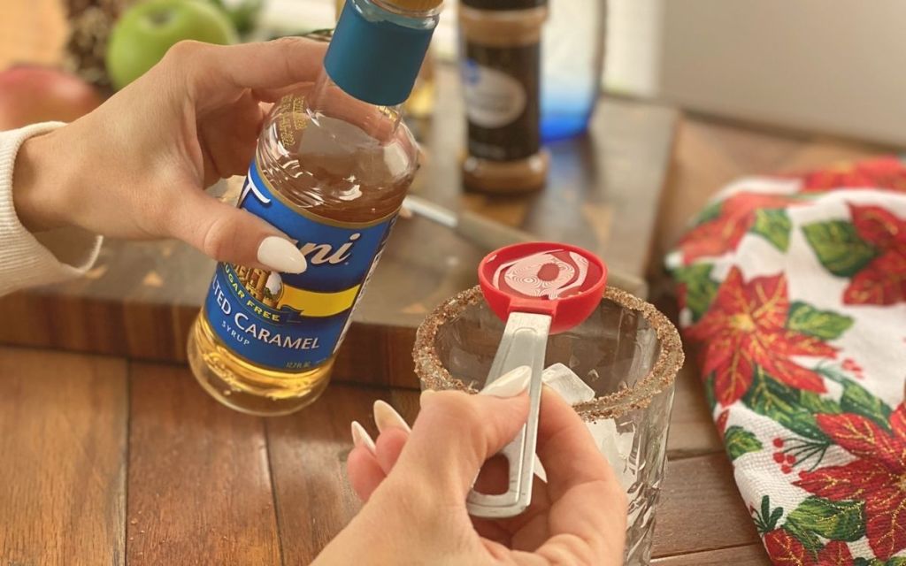 Hands pouring cocktail ingredients into a glass with ice