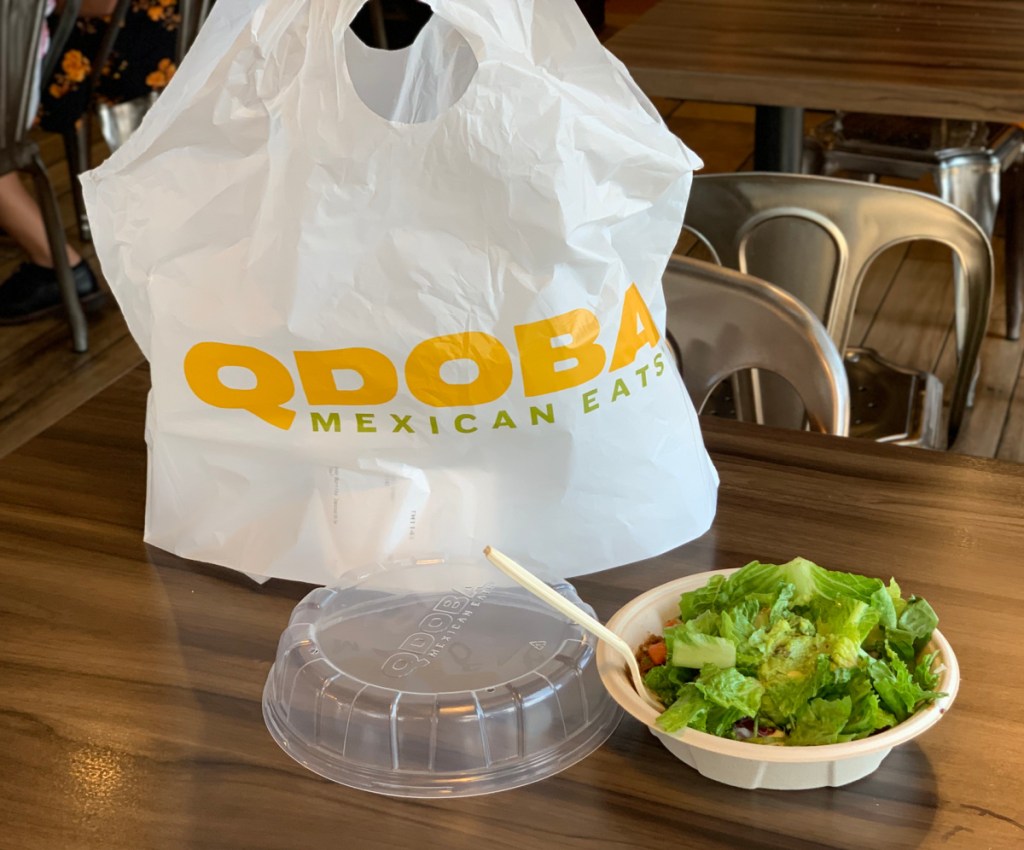A Qdoba bag and low carb Qdoba bowl sitting on a restaurant table
