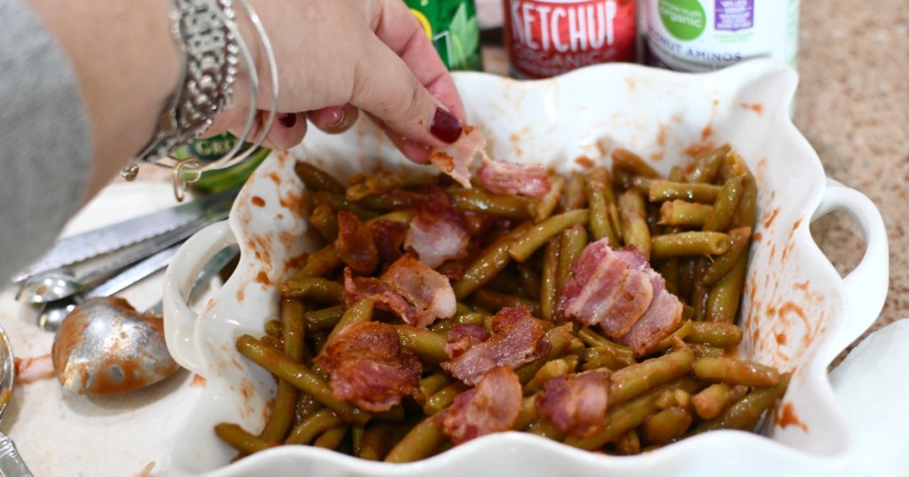 adding bacon to green beans in a casserole dish