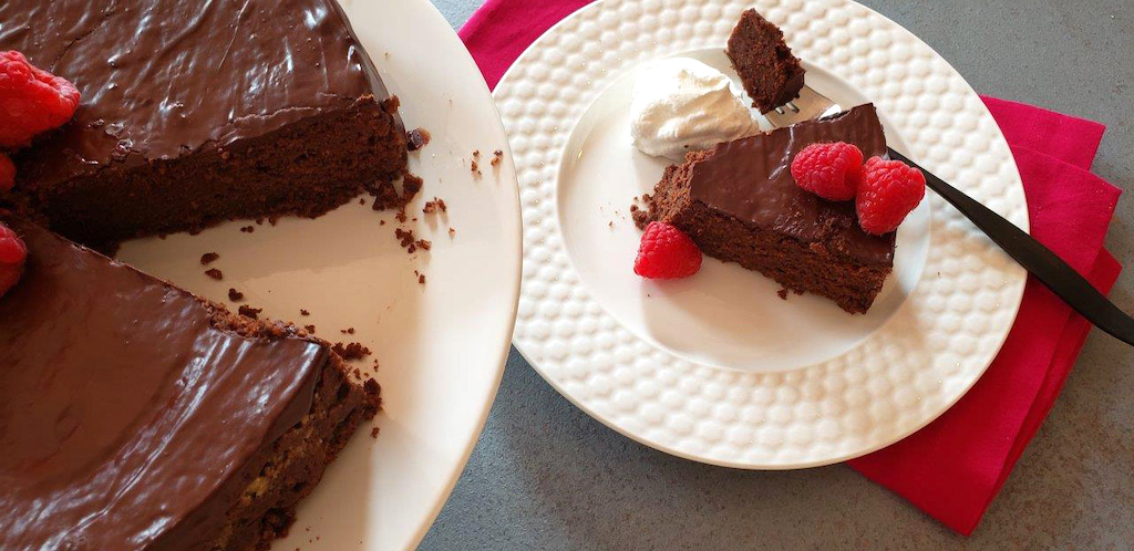 slice of keto chocolate cake on plate with raspberries 