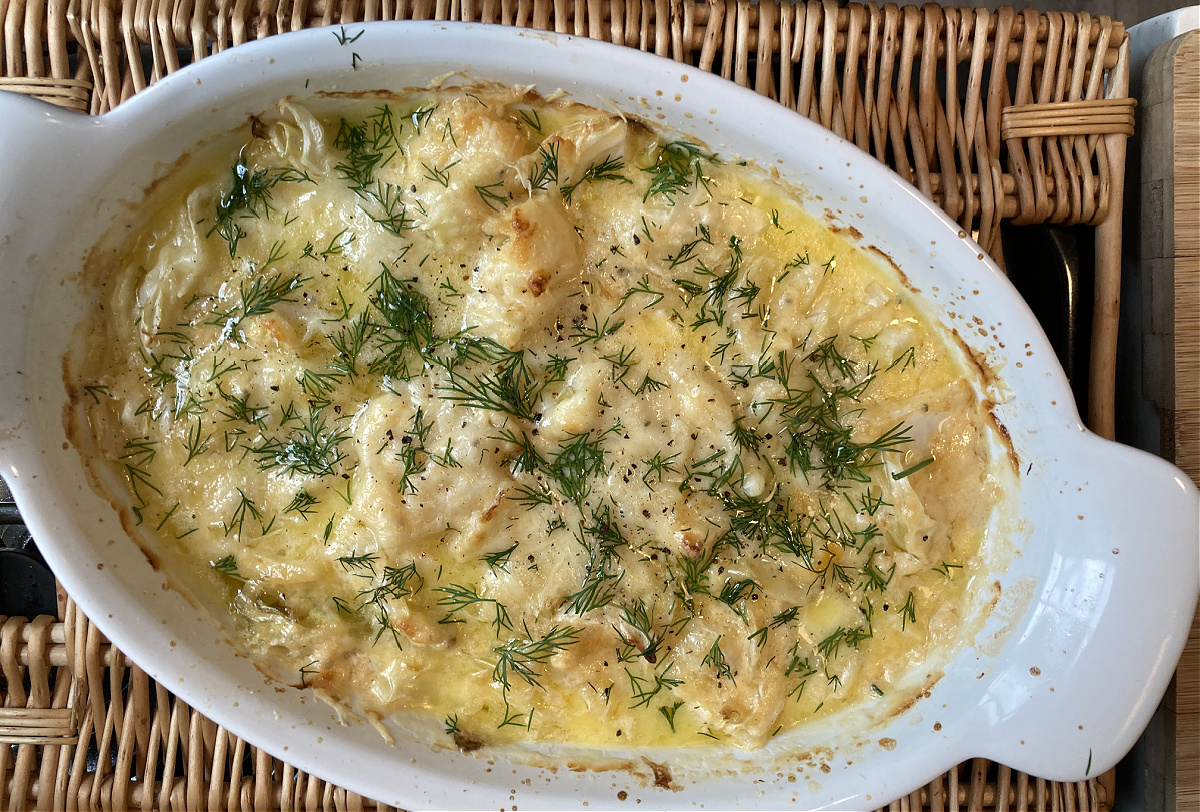 scalloped cabbage in a baking dish with dill garnish on top