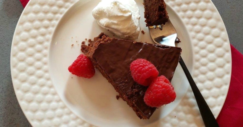 rich slice of keto chocolate cake with raspberries on top 