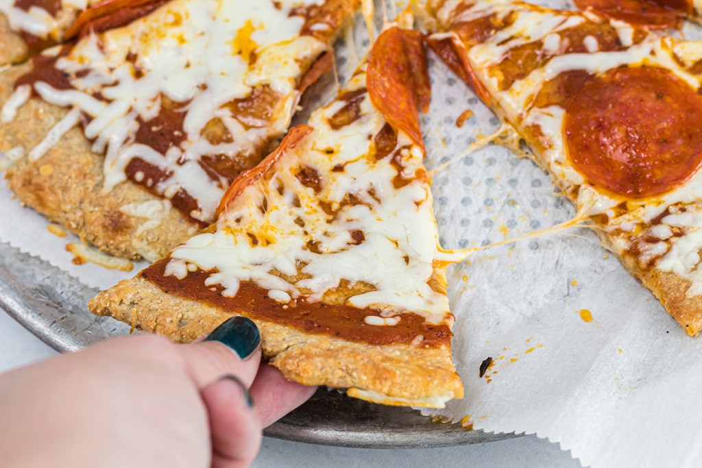 hand grabbing keto pizza slice