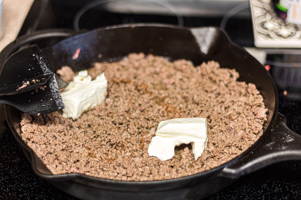 ground beef and cream cheese in cast iron pan