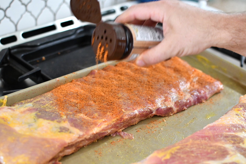putting bearded butcher seasoning on ribs 