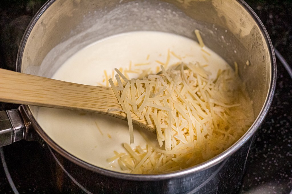 sauce pan with cream and shredded parmesan