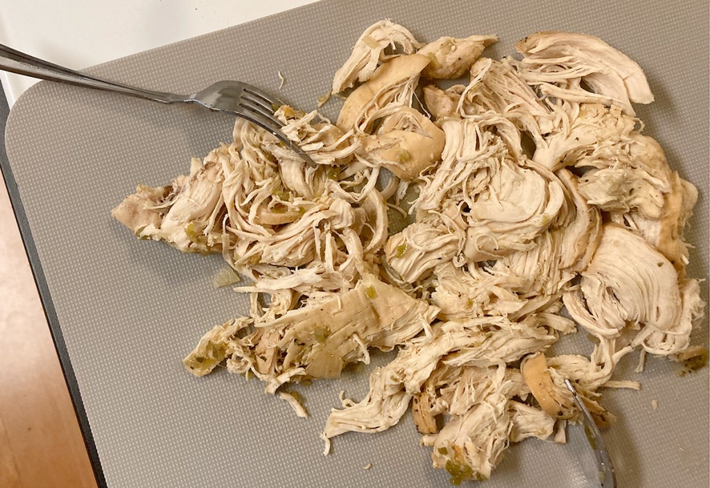 shredded chicken on cutting board with forks