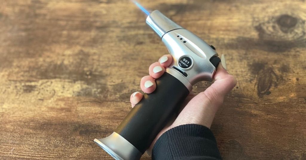 A hand holding a blow torch