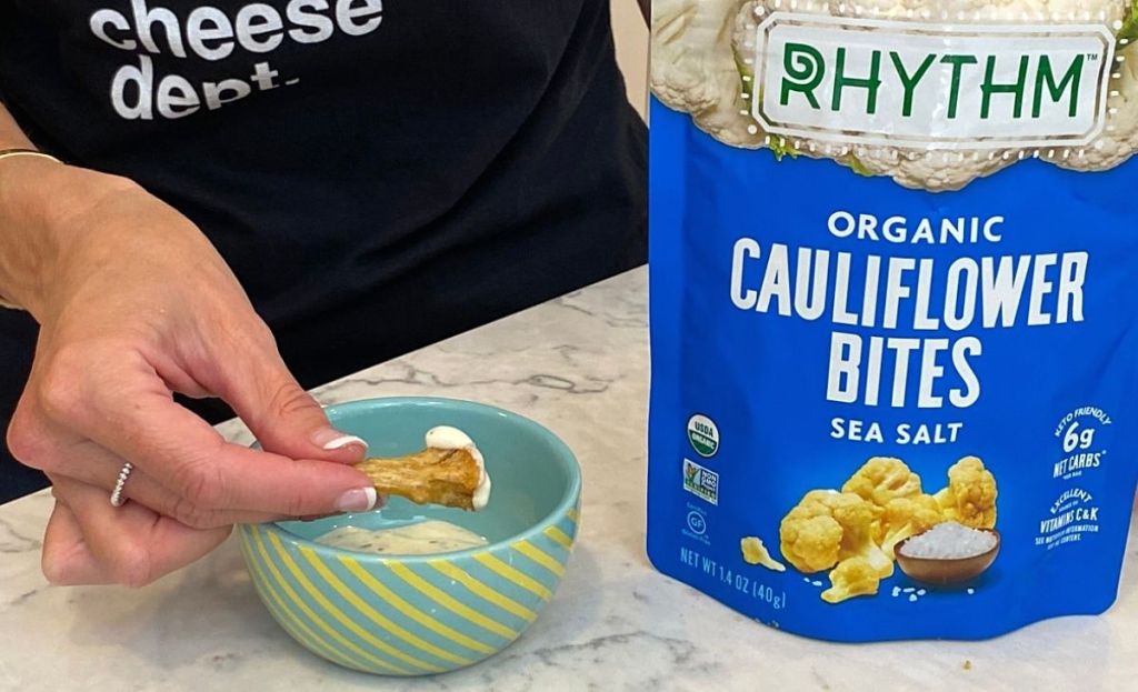 A hand dunking a cauliflower bite into some dip