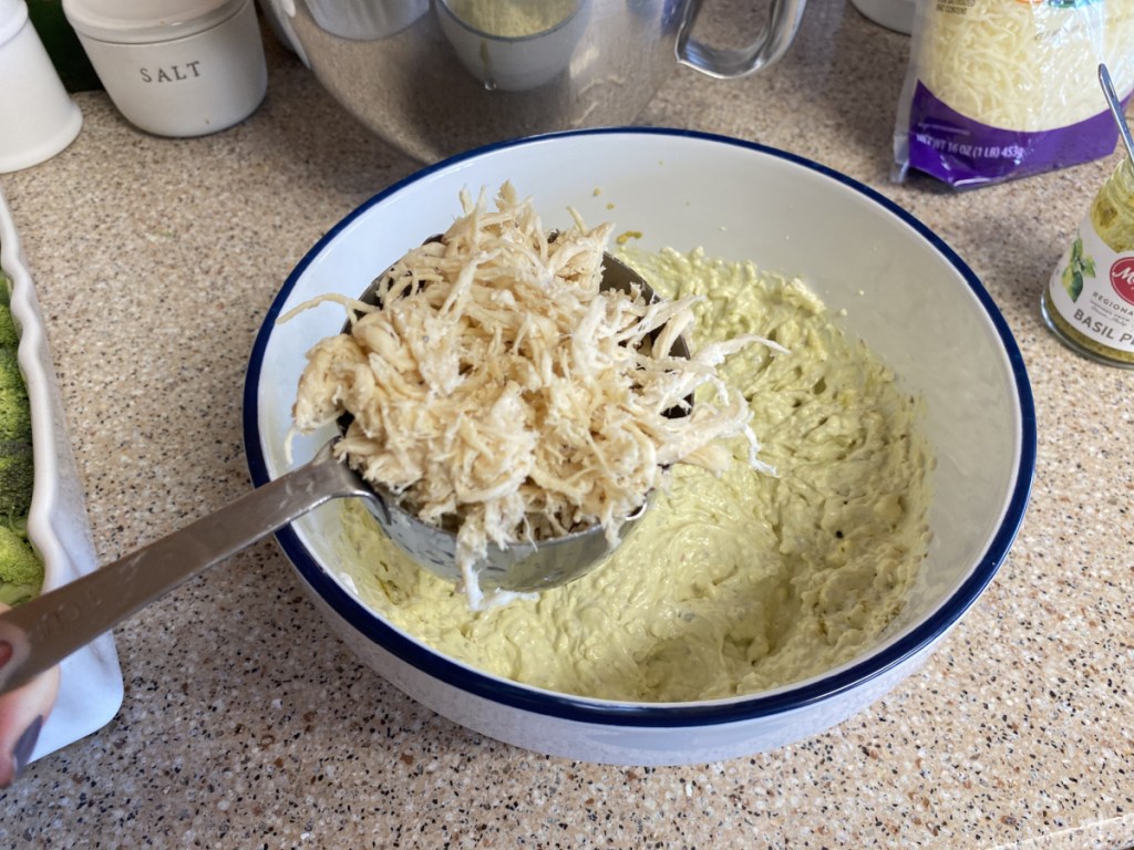 adding shredded chicken to mixing bowl