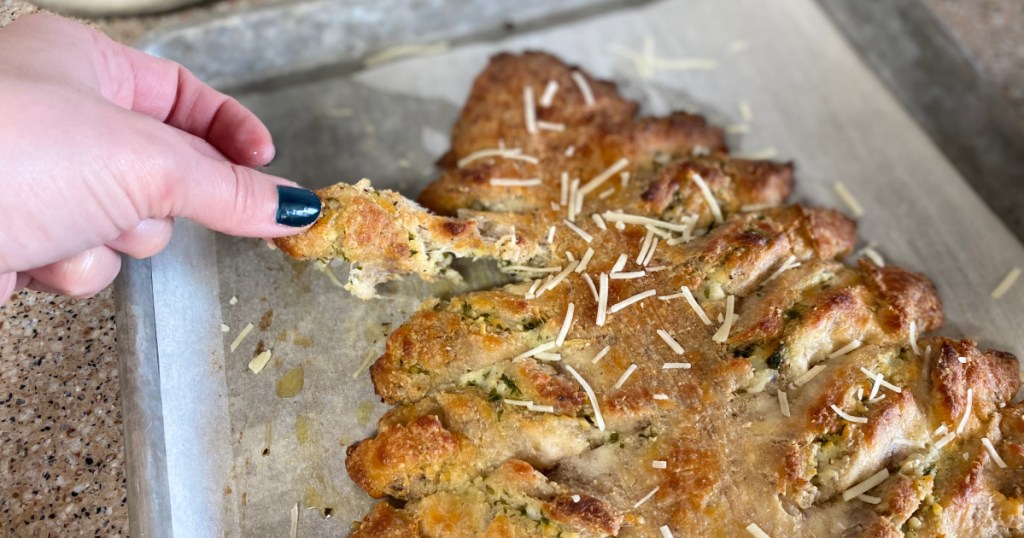 girl pulling breadstick off baking sheet