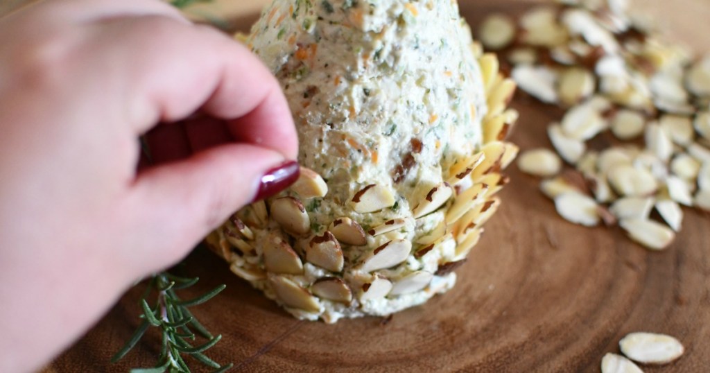 adding almonds to a pine cone shaped keto cheese ball
