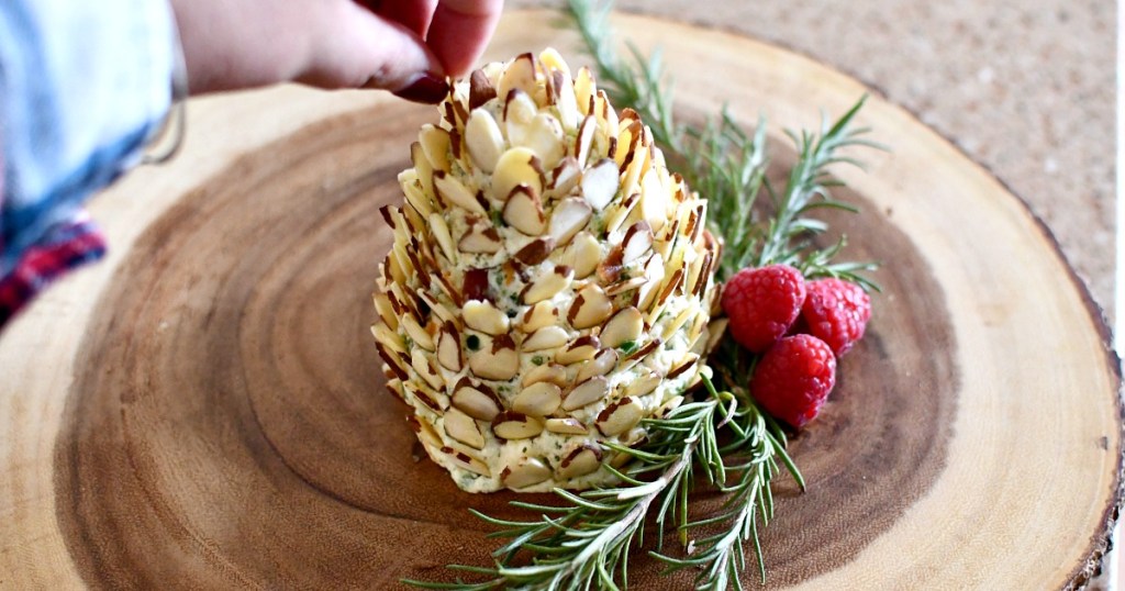 adding almonds to the top of pine cone cheese ball