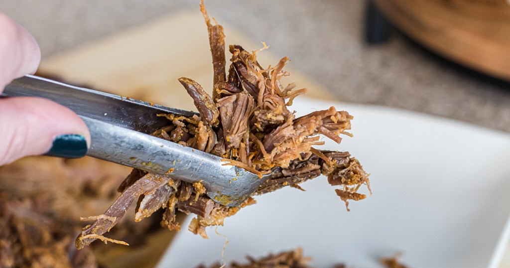 tongs holding keto brisket