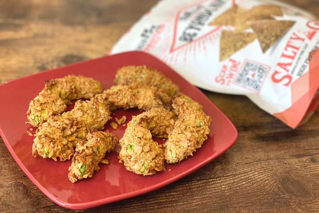 A plate of avocado fries next to a bag of chips