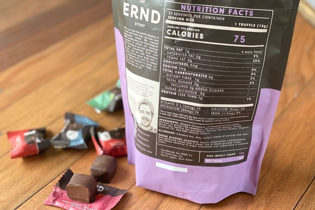 A bag of chocolates displaying nutrition info next to some chocolate pieces on a counter