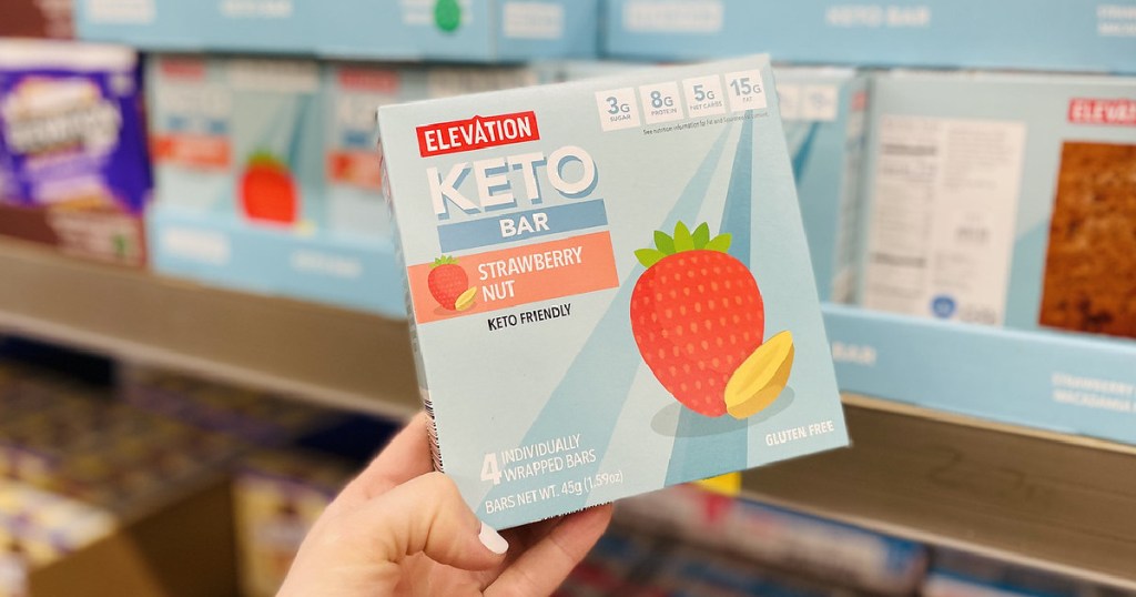 Woman holding a box Elevation Keto Bar from ALDI in strawberry nut flavor