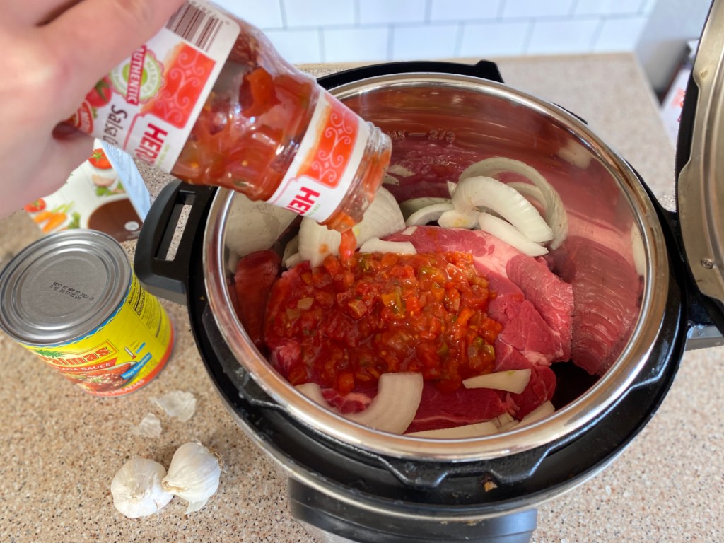 pouring salsa over a roast in an Instant Pot