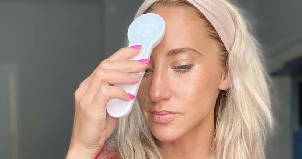 woman taking temperature with thermometer