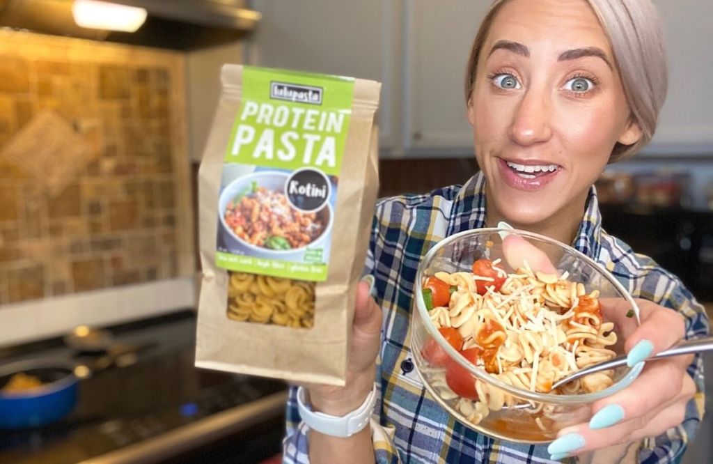 A woman holding a package of pasta and some in a bowl