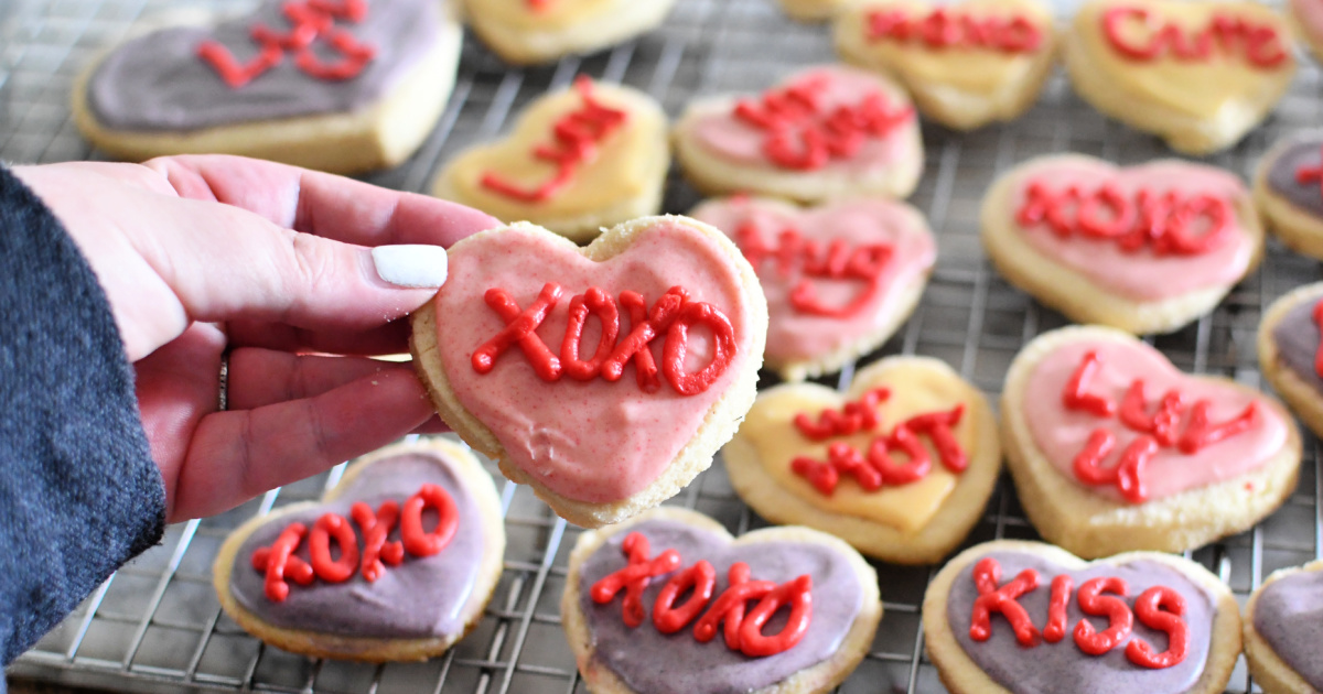 holding a keto conversation heart sugar cookie for valentines day 2024