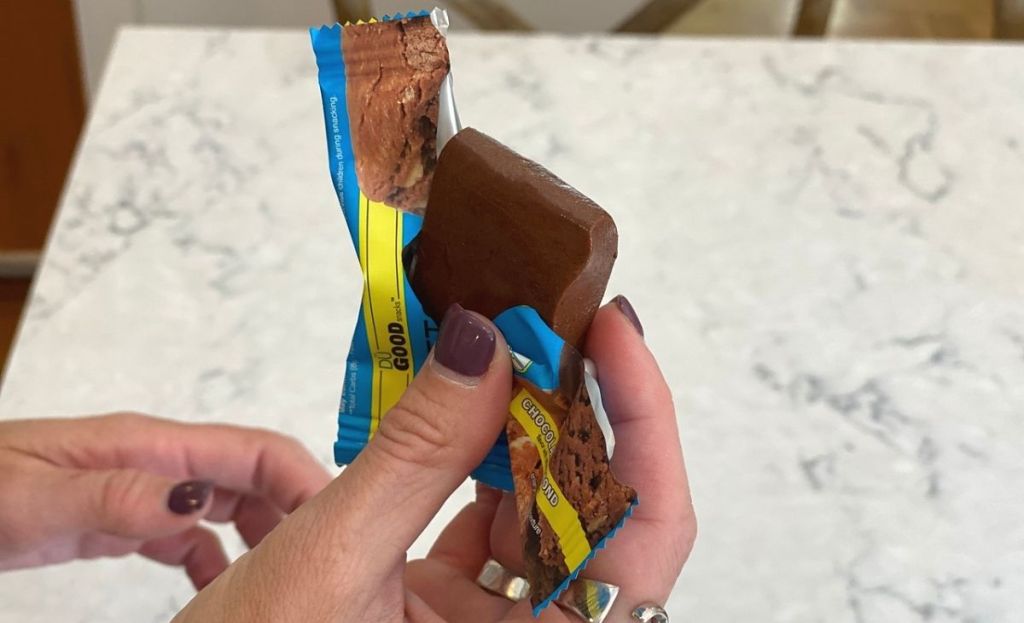 A hand holding a bite-size chocolate in the wrapper